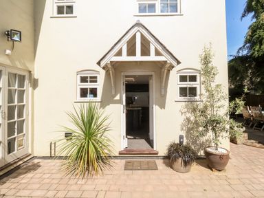 An outdoor patio with potted plants near a doorway entrance of a house at Cavan Cottage in Yoxford
