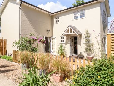 The exterior of a two-story house with a small garden and potted plants at Cavan Cottage in Yoxford