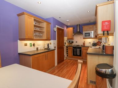 A kitchen with wooden cabinets a gas stove a microwave a toaster and a dining table at Fairfield View in Ambleside