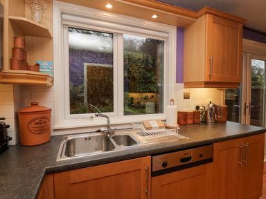 A kitchen with a double sink below a window and wooden cabinets at Fairfield View Ambleside