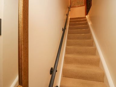 A carpeted staircase with a black handrail and a framed map on the wall at Fairfield View in Ambleside