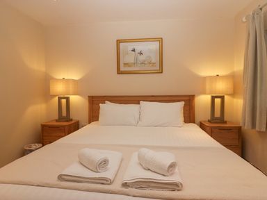 A bedroom with a double bed two bedside tables with lamps and folded towels at Fairfield View Ambleside