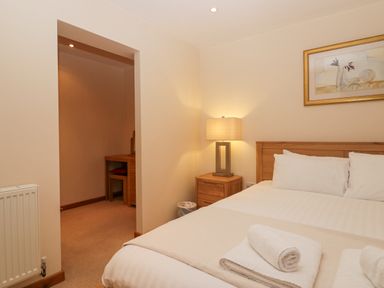 A bedroom with a bed a wooden bedside table with a lamp and a small desk in an alcove at Fairfield View Ambleside