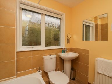 A bathroom with a toilet sink mirror window and towel at Fairfield View in Ambleside