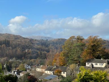 Houses with trees and hills in the background under a blue sky at Fairfield View in Ambleside