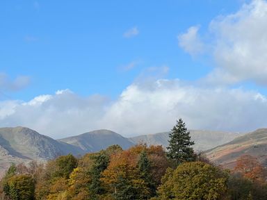 A mountain landscape with trees in autumn colors under a blue sky at Fairfield View in Ambleside
