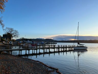 A lakeside with a wooden pier and a sailboat on the water at Fairfield View in Ambleside