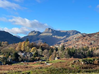 A mountain landscape with trees and houses under a clear blue sky at Fairfield View in Ambleside