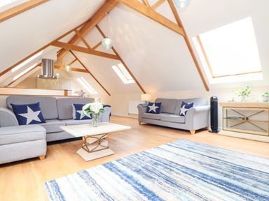 A living room with two grey sofas a coffee table and a blue striped rug at Potters Barn Trevarno near Helston