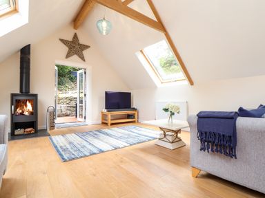 A living room with a wood burning stove television table and skylight at Potters Barn Trevarno near Helston