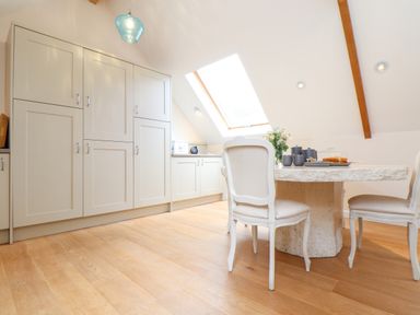 A dining area with a stone table and chairs under a skylight at Potters Barn in Trevarno near Helston