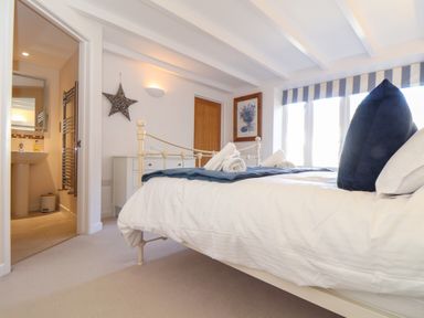 A bedroom with a bed towels wall art and an ensuite bathroom at Potters Barn in Trevarno near Helston