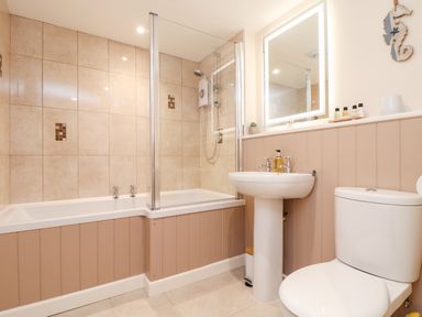 A bathroom with a bathtub shower combination a pedestal sink and a toilet at Potters Barn Trevarno near Helston