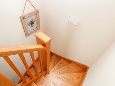 A wooden staircase with a handrail and a framed picture hanging on the wall at Potters Barn in Trevarno near Helston