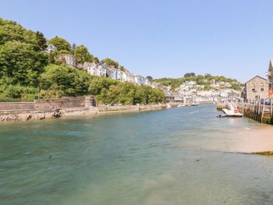 A river with houses on a hillside and buildings along the waterfront at 3 River View in Looe