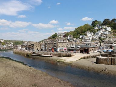 A river with a boat ramp and buildings along the shore with houses on a hill in the background at 3 River View in Looe