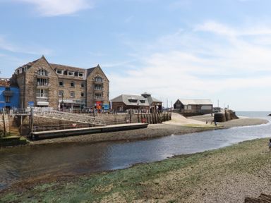 A river with stone buildings and a small pier by the sea at 3 River View in Looe