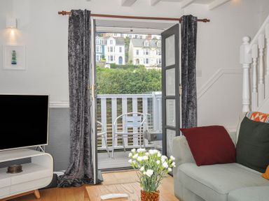 A living room with a TV and a sliding door at 3 River View Looe