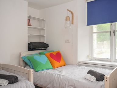 A bedroom with two beds and a shelf at 3 River View in Looe
