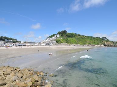 A beach with people and a view of houses on a hill at 3 River View in Looe