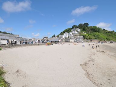 A beach with buildings and people at 3 River View in Looe