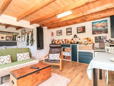 A living space with wooden beams sofa armchair and kitchen area at Dart View Hideout in Totnes