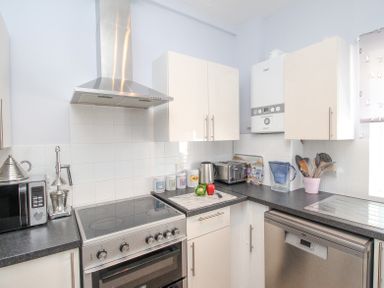A kitchen with stove microwave cabinets and utensils at The Skippers House in Weymouth