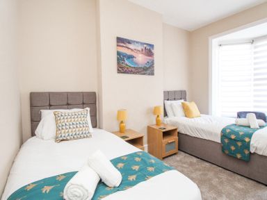 A bedroom with two single beds side by side with bedside tables and lamps at The Skippers House in Weymouth