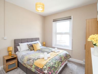 A bedroom with a double bed bedside tables and a window at The Skipper's House in Weymouth