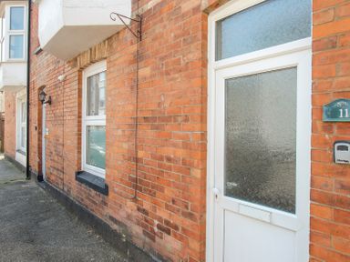 A white door with textured glass and a window on a brick building at The Skipper's House in Weymouth