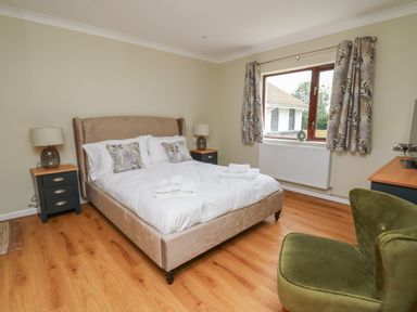 A bedroom with a double bed bedside tables with lamps a green armchair and a window at Sea View in St Clears