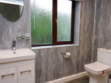 A bathroom with a sink cabinet a mirror a window with patterned glass a toilet and a toilet paper holder at The Oaks in St Clears