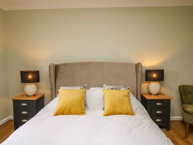 A bedroom with a bed with yellow pillows and bedside tables with lamps at The Oaks in St Clears