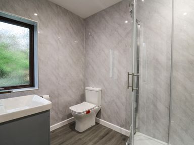 A bathroom with a toilet sink and glass shower enclosure at The Oaks in St Clears