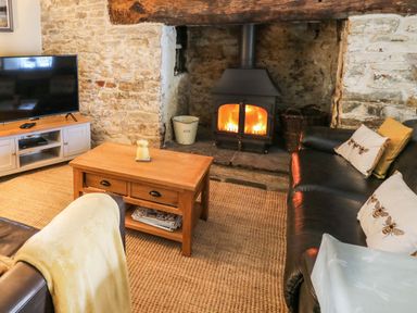 A living room with a fireplace a wooden coffee table a flat screen tv and leather sofas at The Bake House in Bettws
