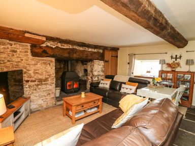 A living room with a wood burning stove wooden coffee table and leather sofas at The Bake House in Bettws