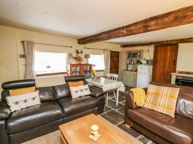 A living room with two leather sofas a wooden coffee table and a dining table with chairs at The Bake House in Bettws