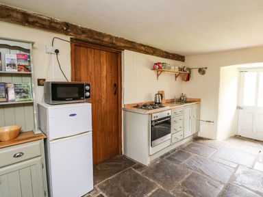 A kitchen with a refrigerator microwave stove oven sink and a wooden door at The Bake House in Bettws