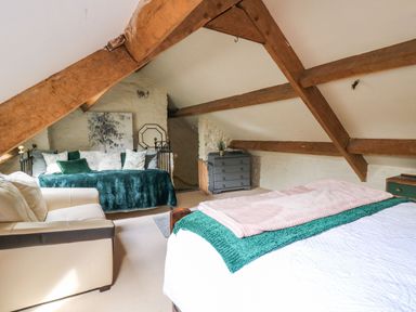 A bedroom with wooden beams a bed a sofa a dresser and a daybed at The Bake House in Bettws