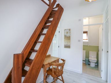 A wooden staircase next to a small wooden desk and chair with a bathroom visible through an open door at Kingfisher in Isleham