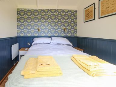 A bedroom with a double bed yellow towels on the bed blue wainscoting and floral wallpaper at Mucklewick Hollow in Minsterley near Bishops Castle