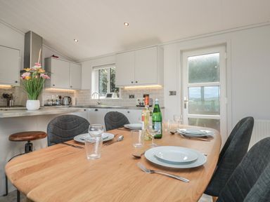 A dining table set with plates glasses and bottles in a kitchen at Bluebell Lodge in Norton near Dartmouth
