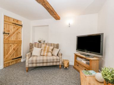 A living room with a plaid sofa and television on wooden furniture at 4 Wallflower Row Mordiford near Hereford