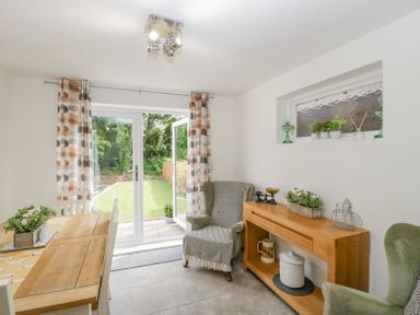 A dining room with a wooden table and chairs a sideboard and open glass doors to a garden at 4 Wallflower Row Mordiford near Hereford