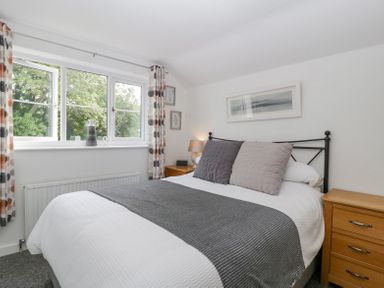 A bedroom with a double bed bedside tables and a window with patterned curtains at 4 Wallflower Row Mordiford near Hereford