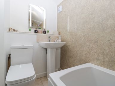 A bathroom with a toilet sink bathtub mirror and decorative items at 4 Wallflower Row in Mordiford near Hereford