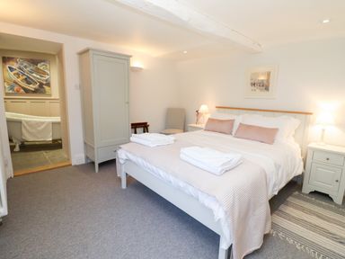 A bedroom with a double bed bedside tables a wardrobe and a view into a bathroom at Spring Cottage in Stroud