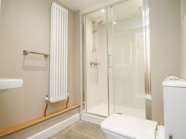 A bathroom with a toilet a shower enclosure a radiator and a towel rail at Spring Cottage in Stroud