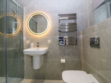 A bathroom with a shower enclosure sink toilet and heated towel rail at Hedd in Amlwch