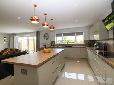 A kitchen with a large island counter and copper pendant lights at Hedd in Amlwch